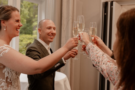 Bruidspaar proosten drankje met ceremoniemeester op bruiloft