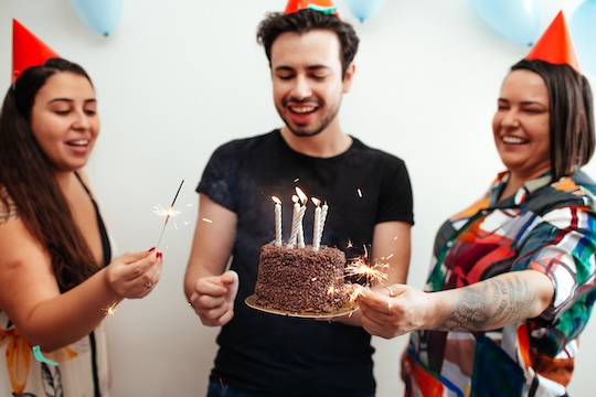 3 mensen die een taart met kaarsjes vasthouden