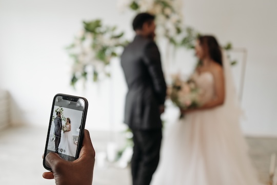 Persoon maakt foto van bruidspaar met een telefoon