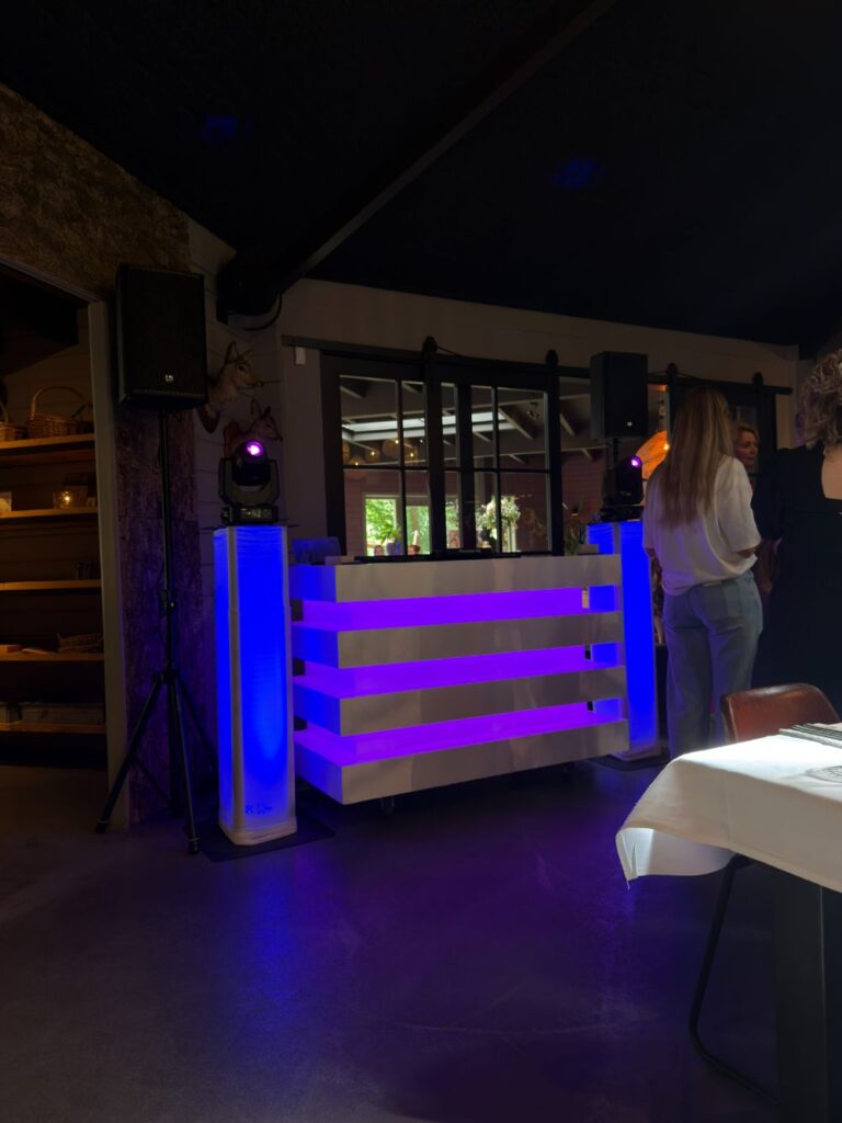 Verlichte DJ booth van Grand Events met moving heads naast de dansvloer