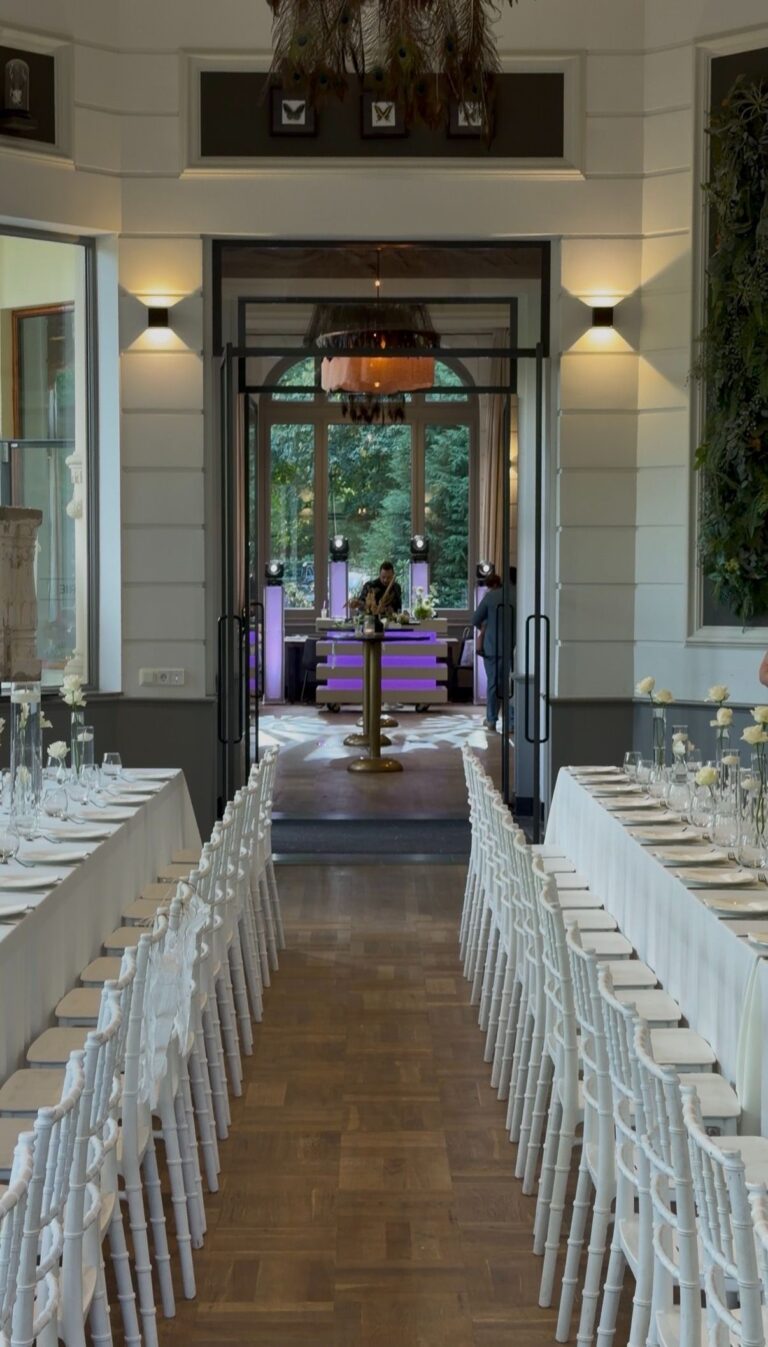 Gedekte tafels in Oranjerie Hydepark met de DJ booth van Grand Events in de zaal erachter